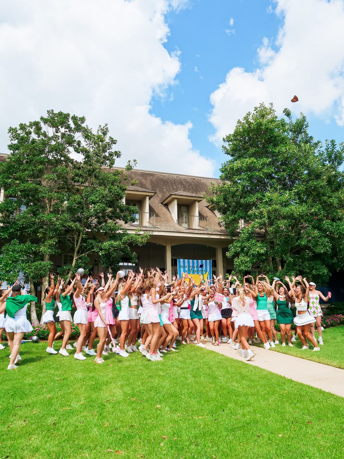Alpha Delta Pi members celebrating in front of the chapter house under a Masters-themed banner