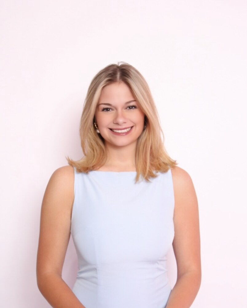 Headshot of Sofie Finnerty smiling in a light blue sleeveless top against a white background